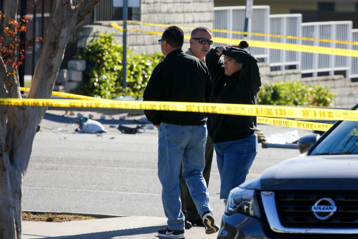 Three people stand together near a car crash site in Whittier.
