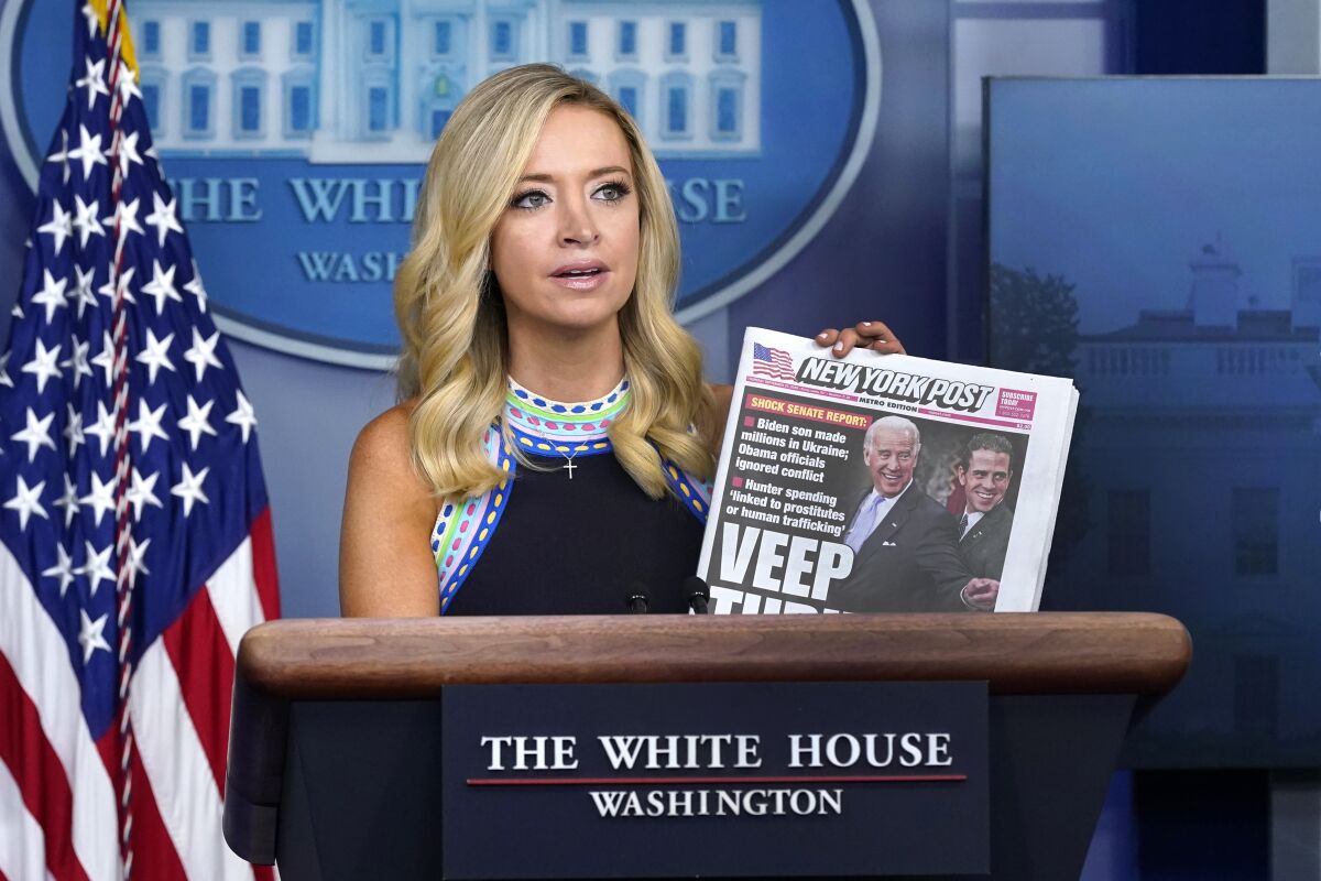 Kayleigh McEnany holds up a tabloid at a press conference