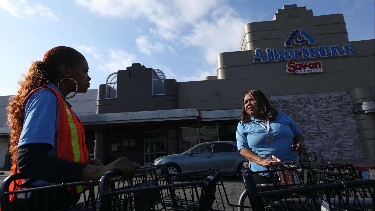 Pamela Hill, right, a cashier at an Albertsons store on Crenshaw Boulevard in Los Angeles, talks with a co-worker about the possibility of a strike.