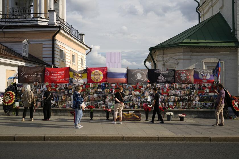 People stand near an improvised memorial to Russian mercenary chief Yevgeny Prigozhin and others who died in a plane crash with him last year, near the Kremlin, in Moscow, Russia, on Monday, July 29, 2024. The Russian mercenary group Wagner suffered its heaviest loss in Africa's Sahel region late last week following an attack that was launched separately by both local and al-Qaida-linked rebels. At least 50 Wagner fighters were reported killed in the attack which raised questions about the group's capacity and whether such an attack could pose any setback to its activities. (AP Photo/Pavel Bednyakov)