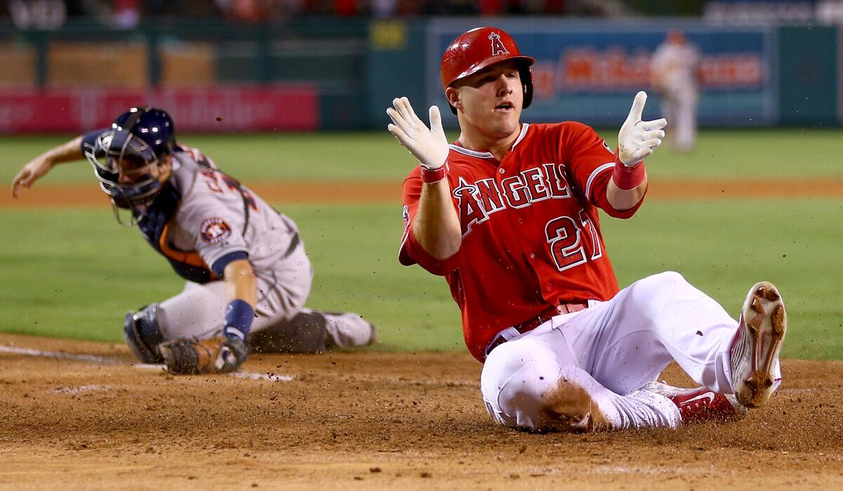 Angels center fielder Mike Trout celebrates as he slides safely past Astros catcher Jason Castro in the fourth inning Friday night in Anaheim.