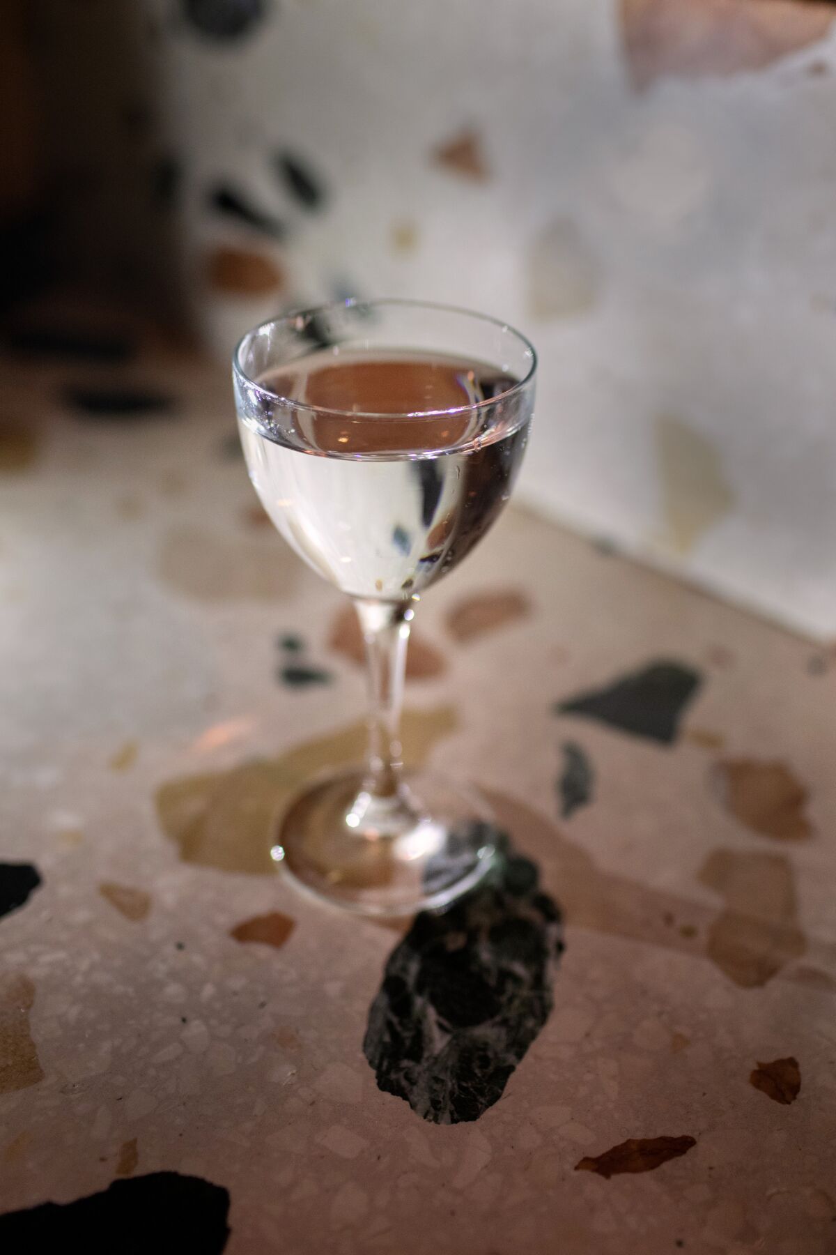 A clear cocktail sits in a glass on the terrazzo bar.