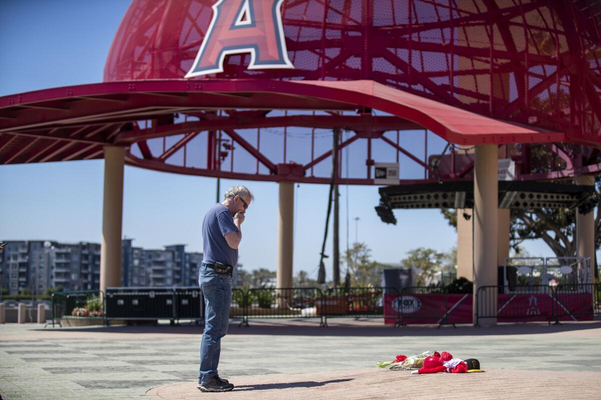 After placing a bouquet of flowers down in front of Angel Stadium, Angels fan Bob Horan spends a quiet moment by himself.