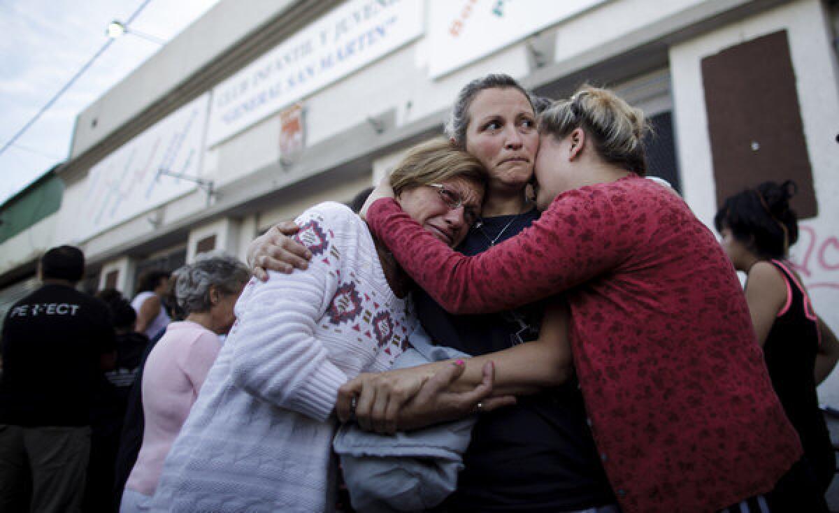 People embrace outside a club where the Red Cross set up a center to help flood victims in La Plata, Argentina, on Thursday.