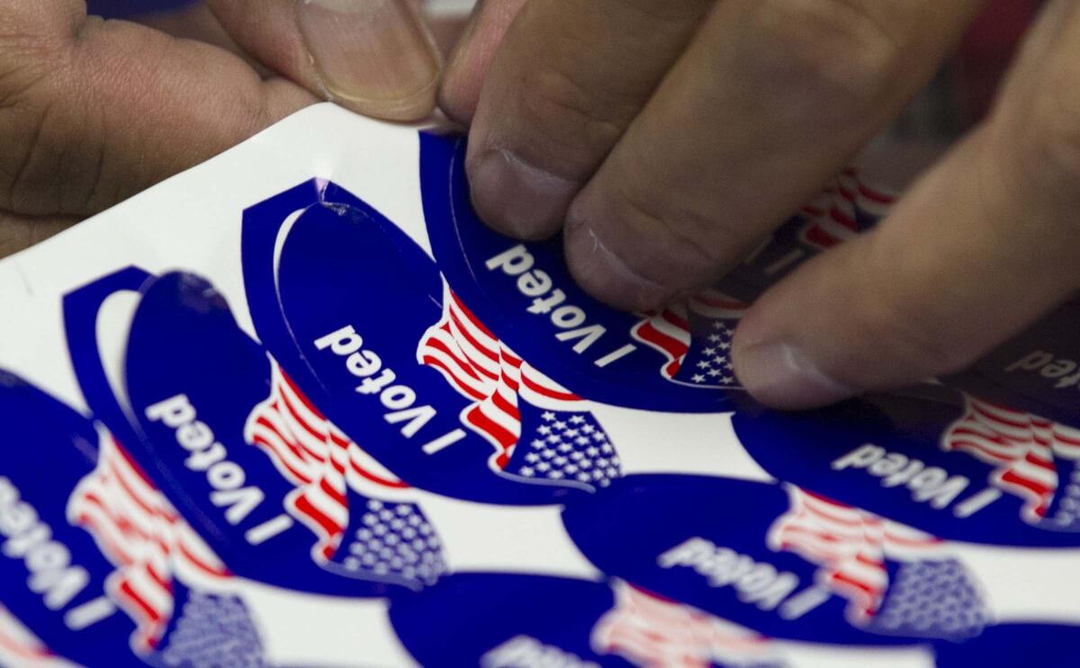 John Gibbins  U-T A poll worker peeled off stickers to hand out to voters showing at a San Diego polling station on Election Day in 2018.