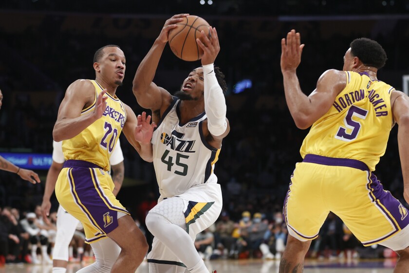 Jazz guard Donovan Mitchell drives between Lakers guards Avery Bradley (20) and Talen Horton-Tucker (5).