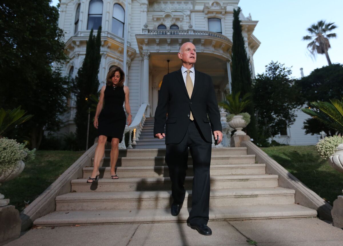 Gov. Jerry Brown and his wife, Anne Gust Brown, walk outside the governor's mansion in June 2014. They plan to move into the historic house with their two dogs in the coming months, making Brown the first governor to live there in decades.