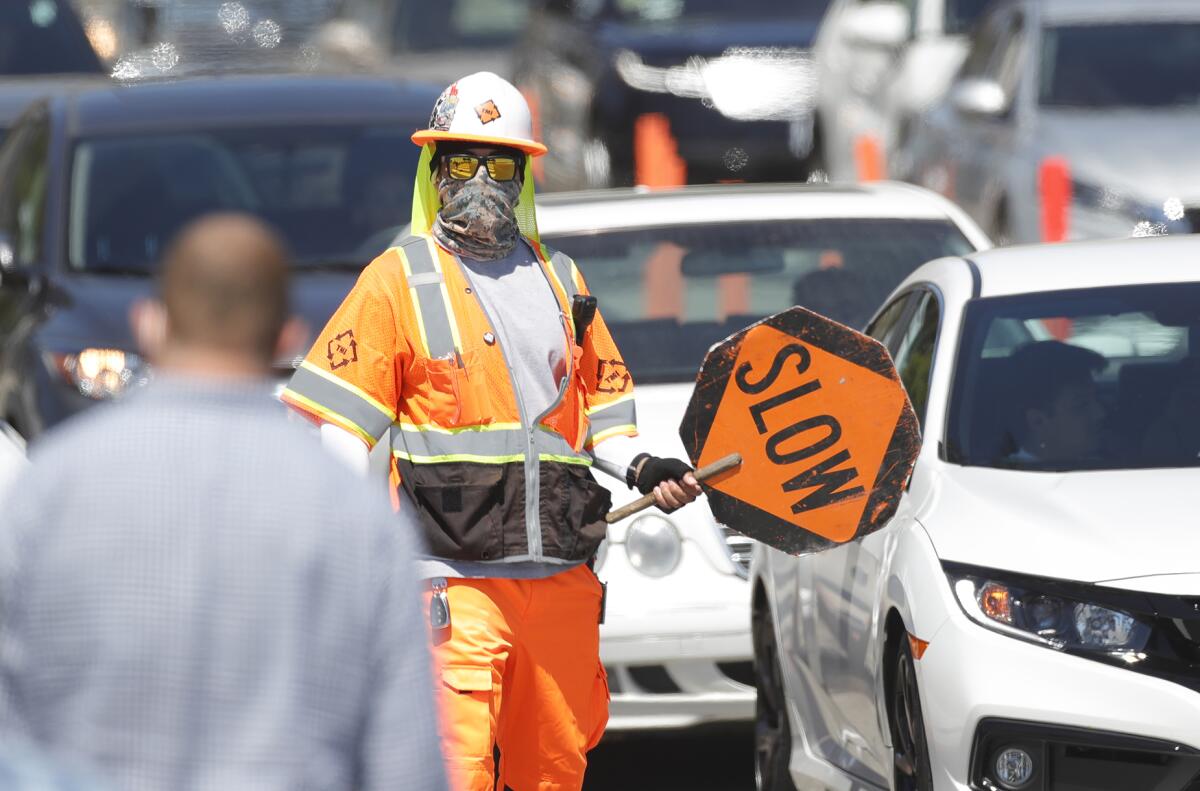 A traffic controller keeps pedestrians safe at Coast Highway and Broadway near the Laguna box culvert construction project.