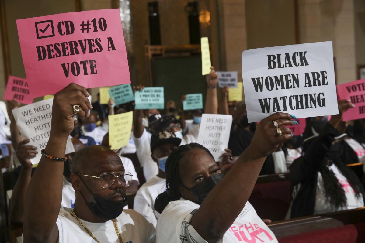 People sitting in benches hold pink and white signs