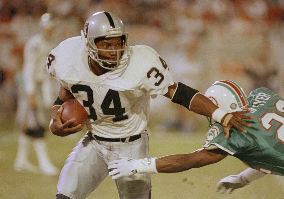 Raiders running back Bo Jackson pushes away Miami Dolphins corner back Tim McKyer 