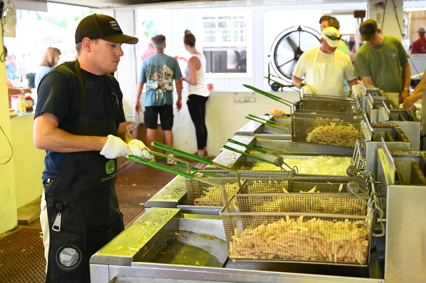 Jeff Schaeffer dips french fries in hot oil, preparing orders for fairgoers during the carnival at Reese & Community Volunteer Fire Company on Tuesday, July 16.