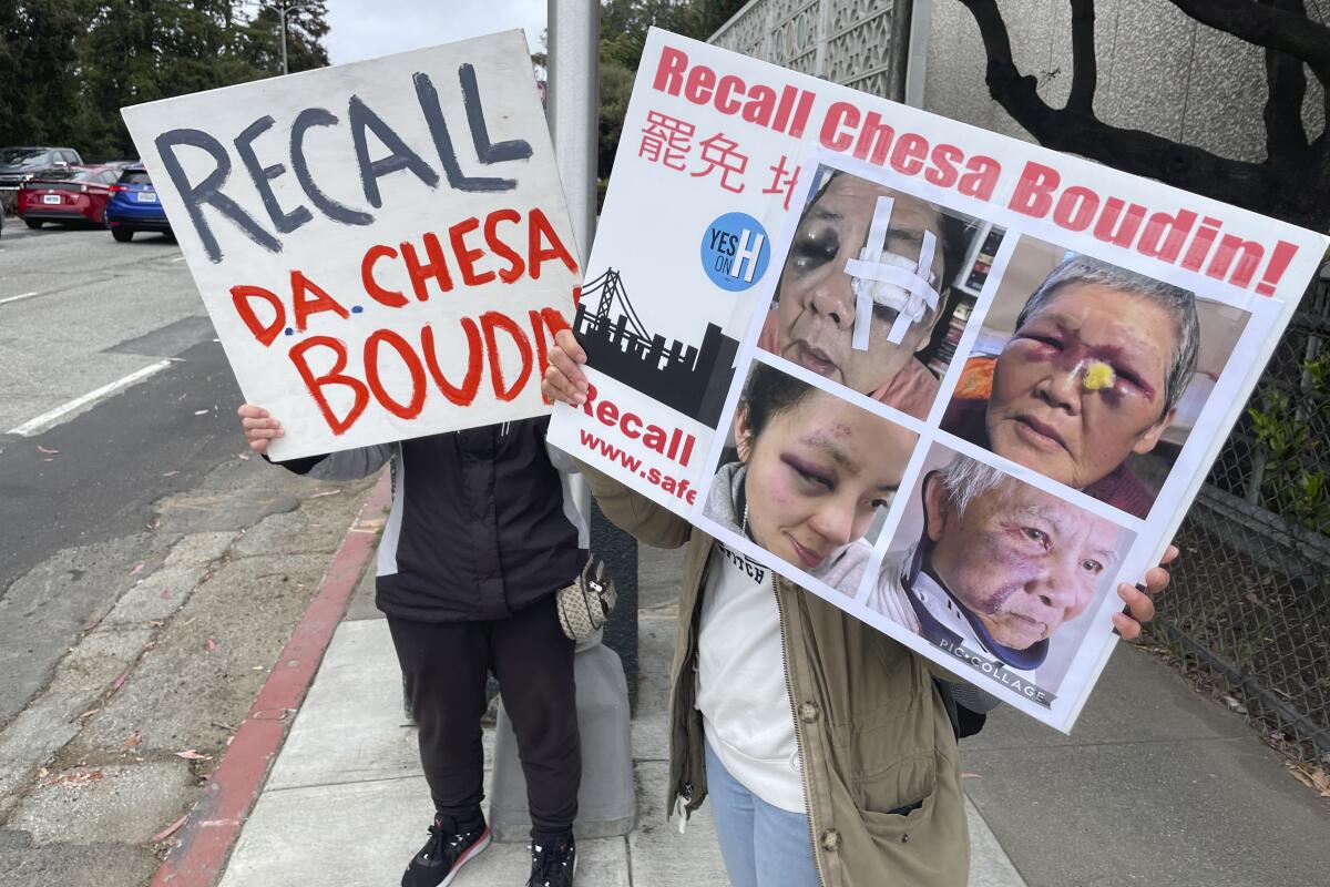 Volunteers with signs stand along 19th Avenue urging motorists to recall District Attorney Chesa Boudin in San Francisco.