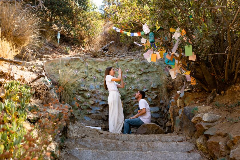 Los Angeles, CA - August 28: Martina Pontremoli photographs the prayer tree with Simon Luculano atop the Buddha trail in Runyon Canyon Park, hours before boarding their flight home to Italy, on Sunday, Aug. 28, 2022 in Los Angeles, CA. (Wesley Lapointe / Los Angeles Times)