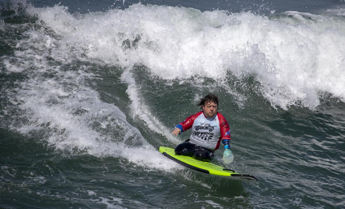 Martin Pollock surfs with help from a device he created to paddle. The former British Army rifleman lost his legs and part of his left arm to an explosion in Afghanistan in 2010.