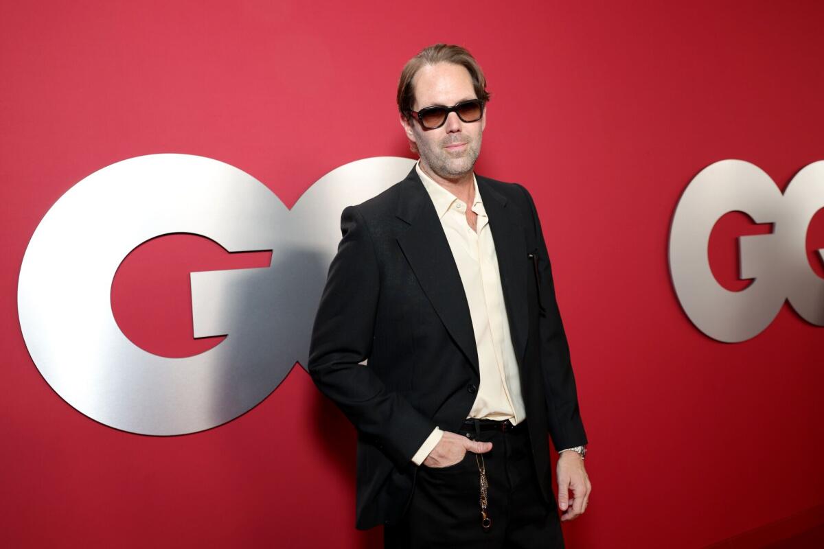 Alan Dye in a dark jacket and light colored button down shirt and tinted glasses attending a GQ event.
