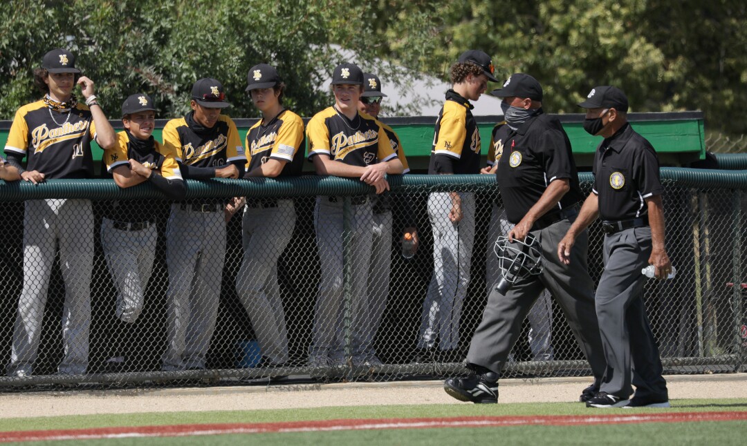 Two umpires walk past Newbury Park players before a game.