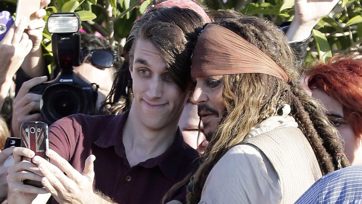 Johnny Depp, dressed as Captain Jack Sparrow from the "Pirates of the Caribbean" movies, poses with a fan after a day on the set of the fifth film in the franchise.