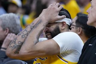 Lakers forward Anthony Davis winces and holds his head on the bench