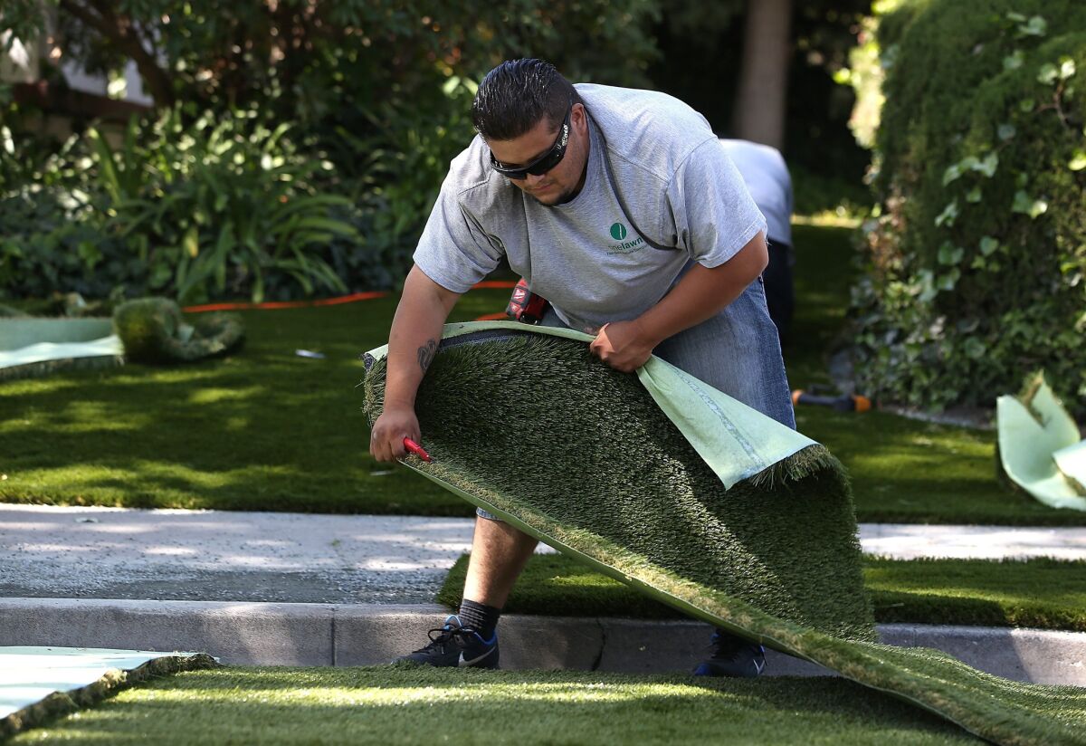 Juan Martinez of landscaping company Onelawn installs a section of artificial lawn at a home in Burlingame, Calif.