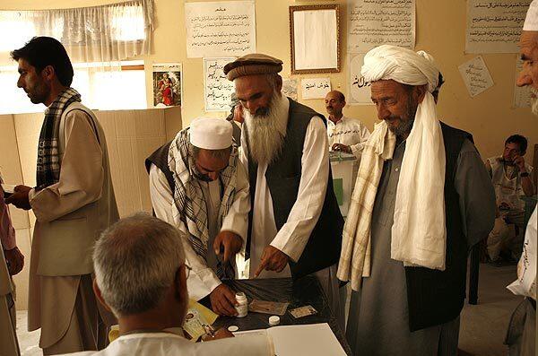 Election workers at a polling station in north Kabul check voters' names before allowing them to dip their fingers in ink as proof that they voted.
