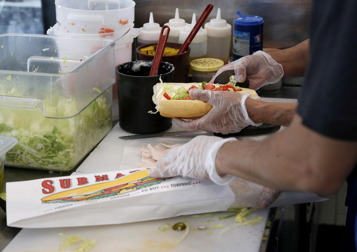 Longtime employees Jaimee Soto and Jose Andrade build sandwiches.