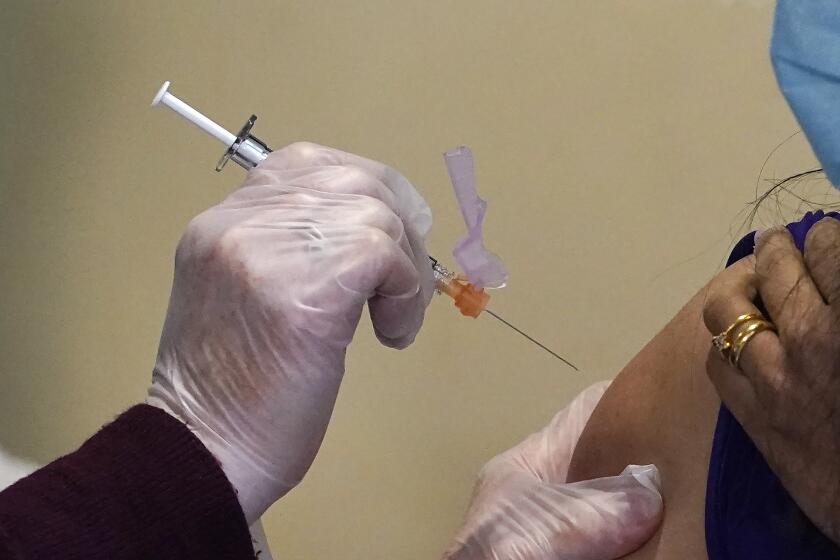 FILE - Registered nurse Allison Miller administers one of the first Pfizer-BioNTech COVID-19 vaccinations at UW Medicine Tuesday, Dec. 15, 2020, in Seattle. Several states have been told to expect far fewer doses of Pfizer’s COVID-19 vaccine in its second week of distribution, but the reason remains a mystery as the company said Thursday, Dec. 17, that its production expectations remain unchanged.(AP Photo/Elaine Thompson, File)