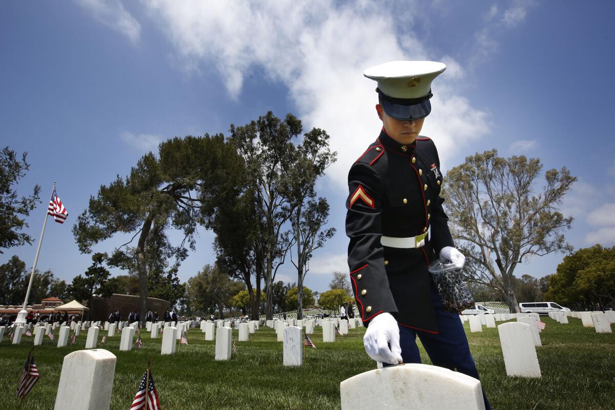 Marine Pfc. Morgan Weibel?places a penny for?the fallen at a Memorial Day celebration at the Los Angeles National Cemetery.
