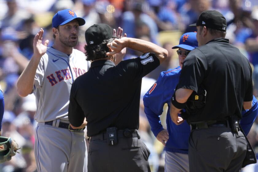 New York Mets starting pitcher Max Scherzer, left, is ejected from the game as he and manager Buck Showalter dispute a call from umpire Phil Cuzzi, center, and umpire Dan Bellino, right, after they found a problem with Scherzer's glove during the fourth inning of a baseball game in Los Angeles, Wednesday, April 19, 2023. (AP Photo/Ashley Landis)
