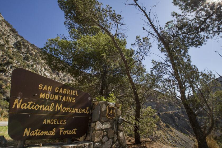 AZUSA, CALIF. -- THURSDAY, AUGUST 13, 2015: A sign is posted at the entrance near Azusa to the San Gabriel Mountains National Monument, Angeles National Forest, as a bicyclist rides past on Aug. 13, 2015.Little has changed in the San Gabriel Mountains in the eight months since President Obama promised that designating the area a national monument would bring new safeguards and visitor improvements. Activists who lobbied for monument status say they are disappointed that no new federal revenue is flowing to the 346,000-acre wilderness, and that the U.S. Forest Service has taken no significant steps to change the way it manages it. The result is that the mountains still have overflowing trash cans, graffiti-covered restrooms, rivers strewn with garbage and little policing. (Allen J. Schaben / Los Angeles Times)