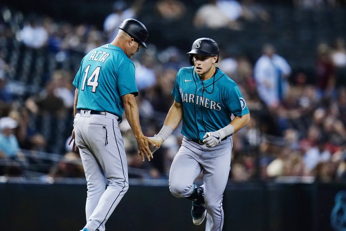 Seattle Mariners' Jarred Kelenic, right, celebrates his two-run home run against the Arizona Diamondbacks with Mariners third base coach Manny Acta (14) during the sixth inning of a baseball game Friday, Sept. 3, 2021, in Phoenix. (AP Photo/Ross D. Franklin)