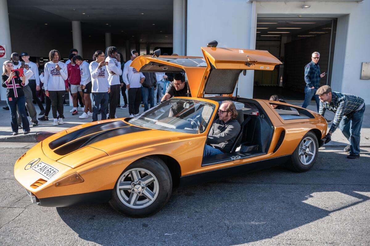 The 1970 Mercedes-Benz Type C 111-II sits on the street, its gull-wing doors open, as workers prepare it for transport