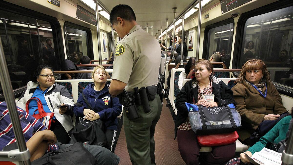 A Los Angeles County Sheriff's Department deputy performs a fare check during a patrol through a Metro train in downtown Los Angeles.