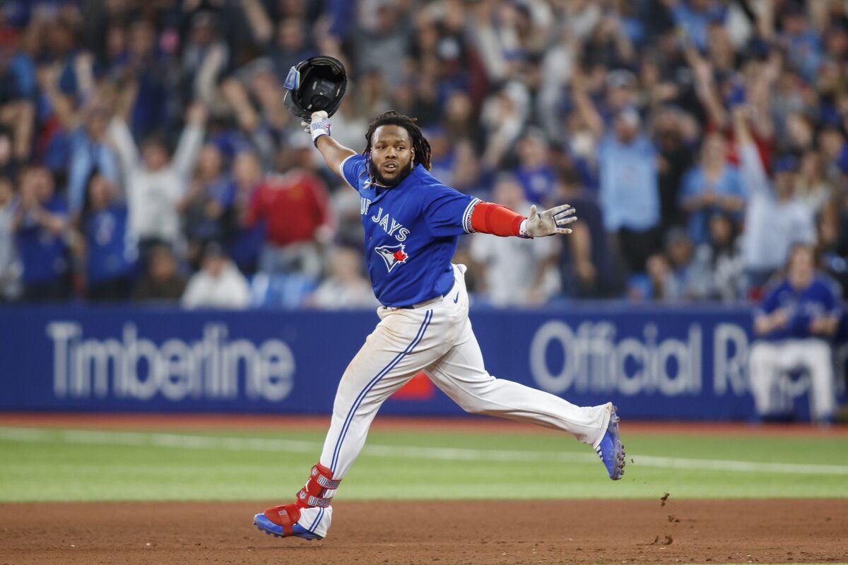 Toronto Blue Jays' Vladimir Guerrero Jr. (27) celebrates after hitting the winning RBI against the New York Yankees in the 10th inning of baseball game action in Toronto, Monday, Sept. 26, 2022. (Cole Burston/The Canadian Press via AP)