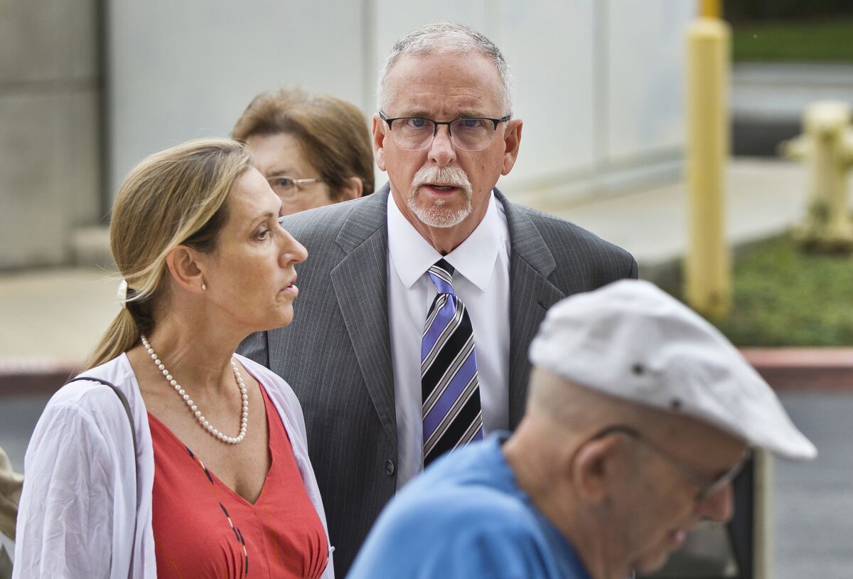 FILE - In this June 26, 2019 file photo UCLA gynecologist James Heaps, center, and his wife, Deborah Heaps, arrive at Los Angeles Superior Court. The University of California has agreed to pay more than $100 million to settle allegations that several hundred women were sexually abused by Heaps. (AP Photo/Damian Dovarganes,File)