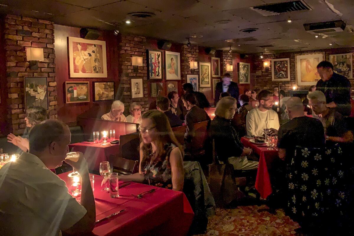 People dining in a dimly lit room with lots of art on the brick walls.