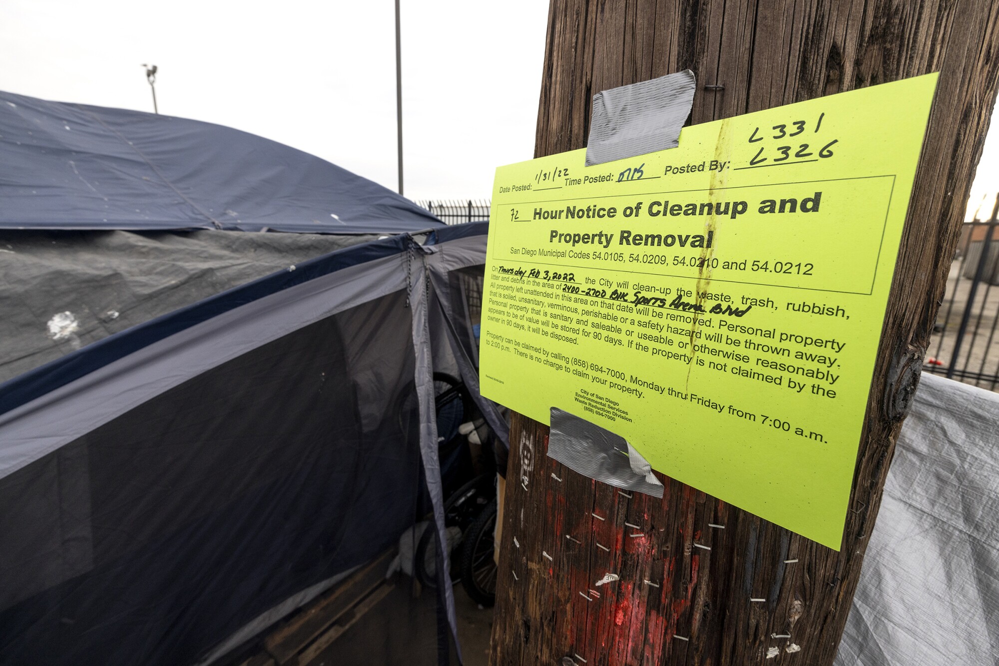 A notice posted on a pole indicating the area where a homeless encampment will be cleared by the city.