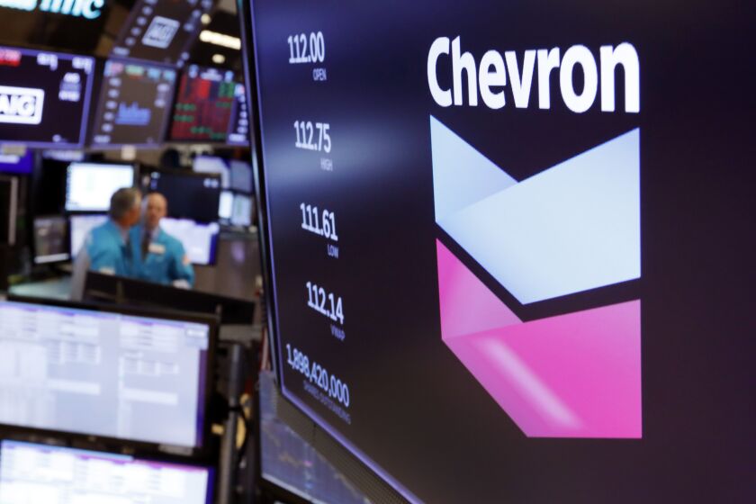 FILE - This Oct. 8, 2019, file photo shows the logo for Chevron on the floor of the New York Stock Exchange. Chevron Corp. reports financial results Friday, Nov. 1. Chevron said Tuesday, Dec. 10, it will book a charge of at least $10 billion because lower long-term prices for oil and natural gas are making some projects less valuable. (AP Photo/Richard Drew, File)