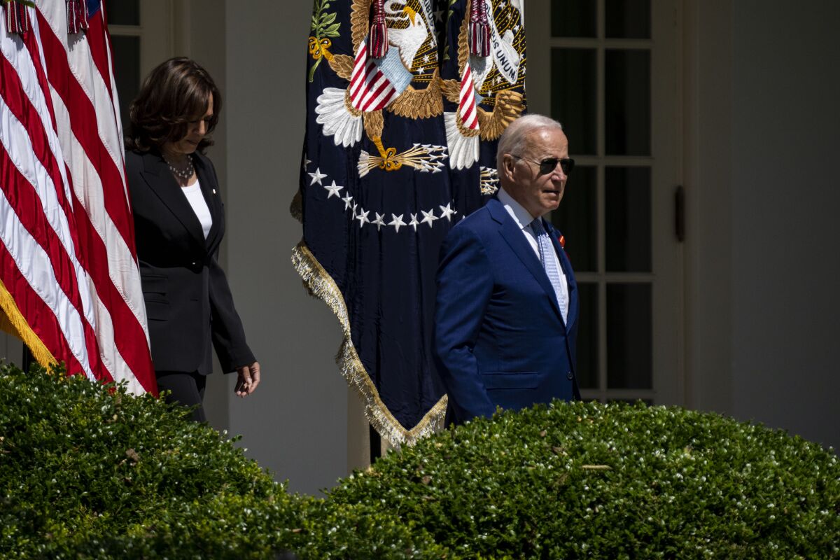 President Biden, Kamala Harris following, walking on the White House grounds heads