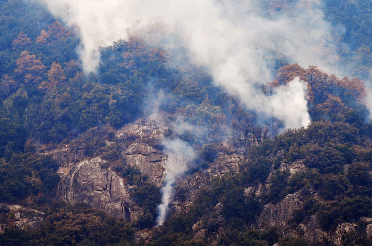 Smoke rises from a tree-filled area adjacent to Moro Rock