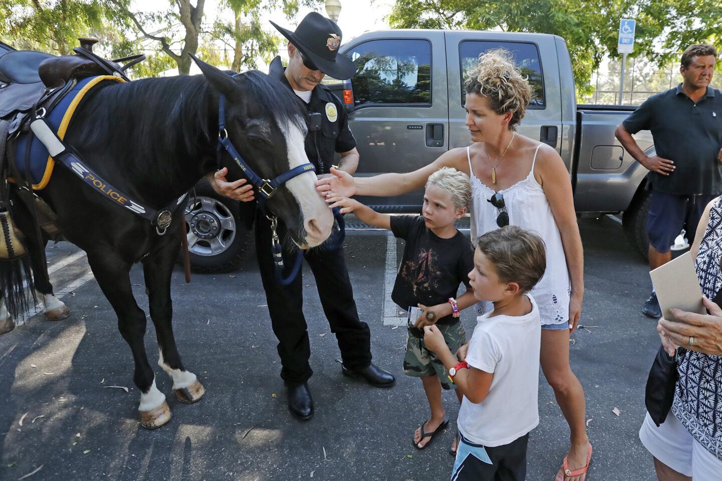 Christie Ferentz and her sons Dylan, 6, bottom left, and Tyler, 4, meet police Officer Matthew Graham and his horse, Stogie, during a Newport Beach public safety fair in celebration of National Night Out on Tuesday at Bonita Canyon Sports Park.