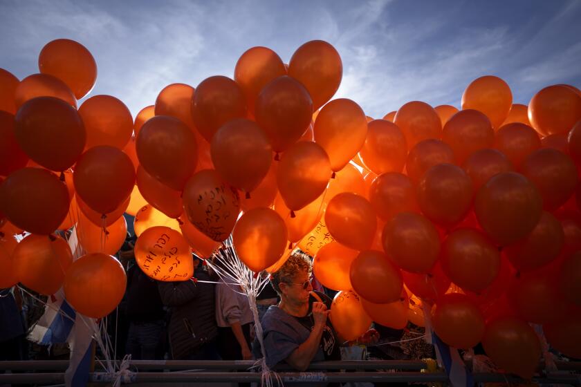 Manifestantes sostienen globos naranjas durante un acto en solidaridad con Kfir Bibas, un bebé israelí que pasó su primer cumpleaños retenido por Hamás en Gaza, en Tel Aviv, Israel, el 18 de enero de 2024. (AP Foto/Oded Balilty)
