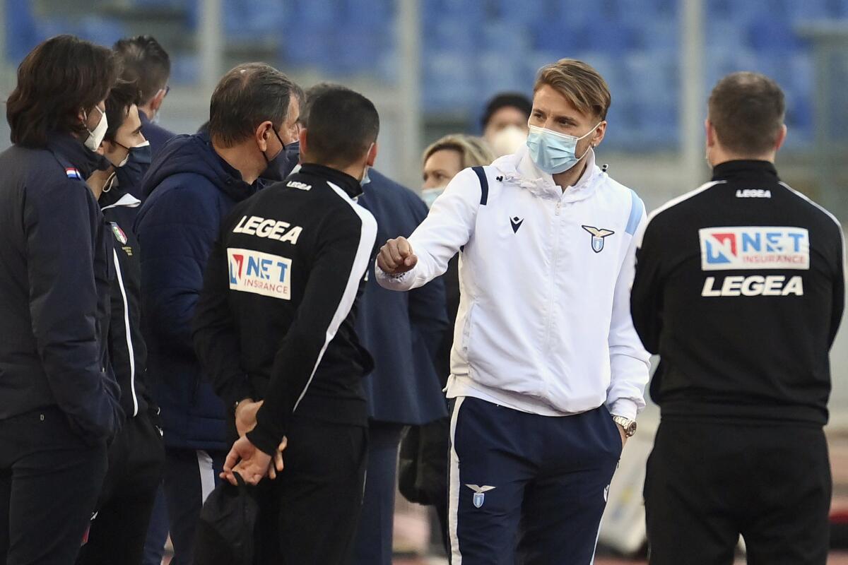 Lazio's Ciro Immobile, 2nd from right, stands on the pitch prior to the Serie a soccer match between Lazio and Torino, at the Rome Olympic Stadium Tuesday, March 2, 2021. Lazio walked out into Stadio Olimpico for its Serie A match on Tuesday even though it knows its Torino opponents are still in Turin. A coronavirus outbreak forced Torino players and staff into self-isolation that doesn't end until midnight Tuesday, hours after the scheduled kickoff against Lazio in Rome. (Alfredo Falcone/LaPresse via AP)