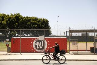 WILMINGTON-CA-JUNE 1, 2022: A man rides a bike past Warren Recreation Park in Wilmington on Wednesday, June 1, 2022. Earlier that morning, Communities for a Better Environment, Standing Together Against Neighborhood Drilling, and U.S. Congresswoman Nanette Barragan held a news conference to allege illegal oil drilling in Wilmington and demand the city of Los Angeles take action against oil operator Warren Resources. (Christina House / Los Angeles Times)