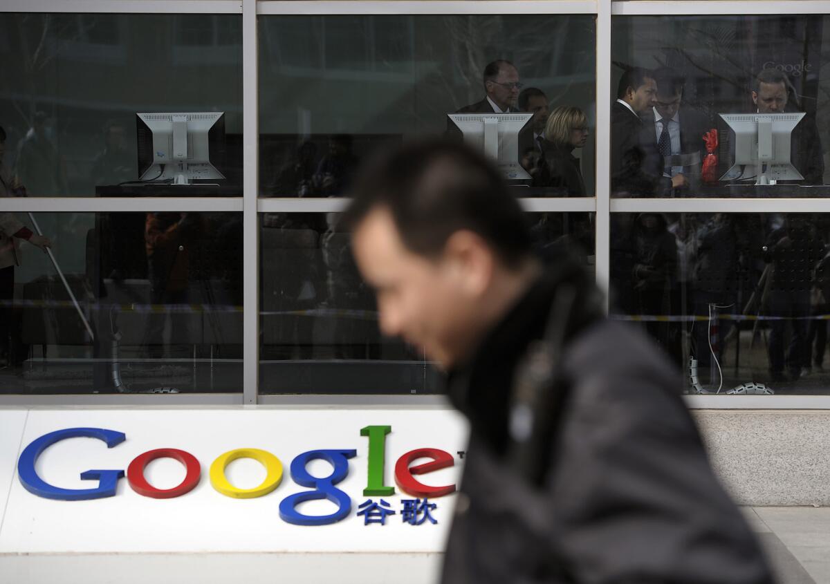 In this March 23, 2010 file photo, a security guard walks past while foreign visitors are seen inside the Google China headquarters in Beijing.