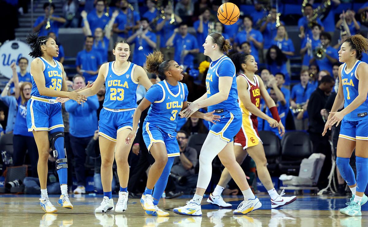 Players on the UCLA women's basketball team celebrate immediately after their 71-64 victory over rival USC.