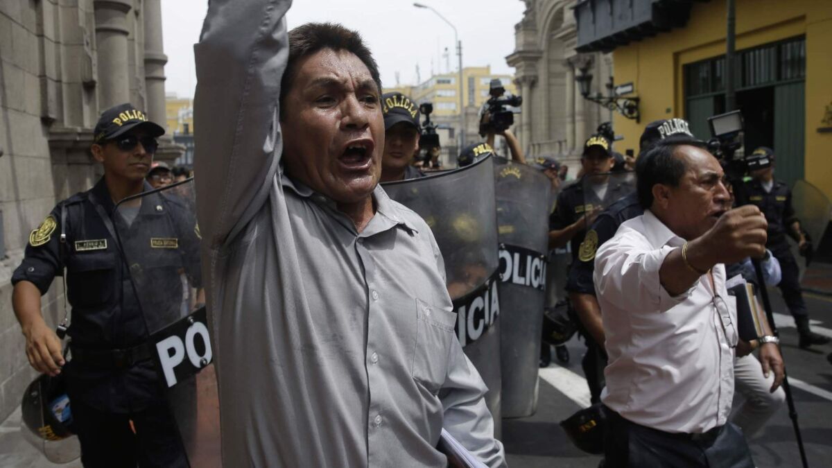 Riot police divert men shouting slogans against Peru's government outside the Government Palace in Lima on March 21, 2018.