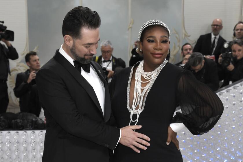 Alexis Ohanian rubs Serena Williams' pregnant belly on the Met Gala carpet. Both are dressed in black-and-white formal attire