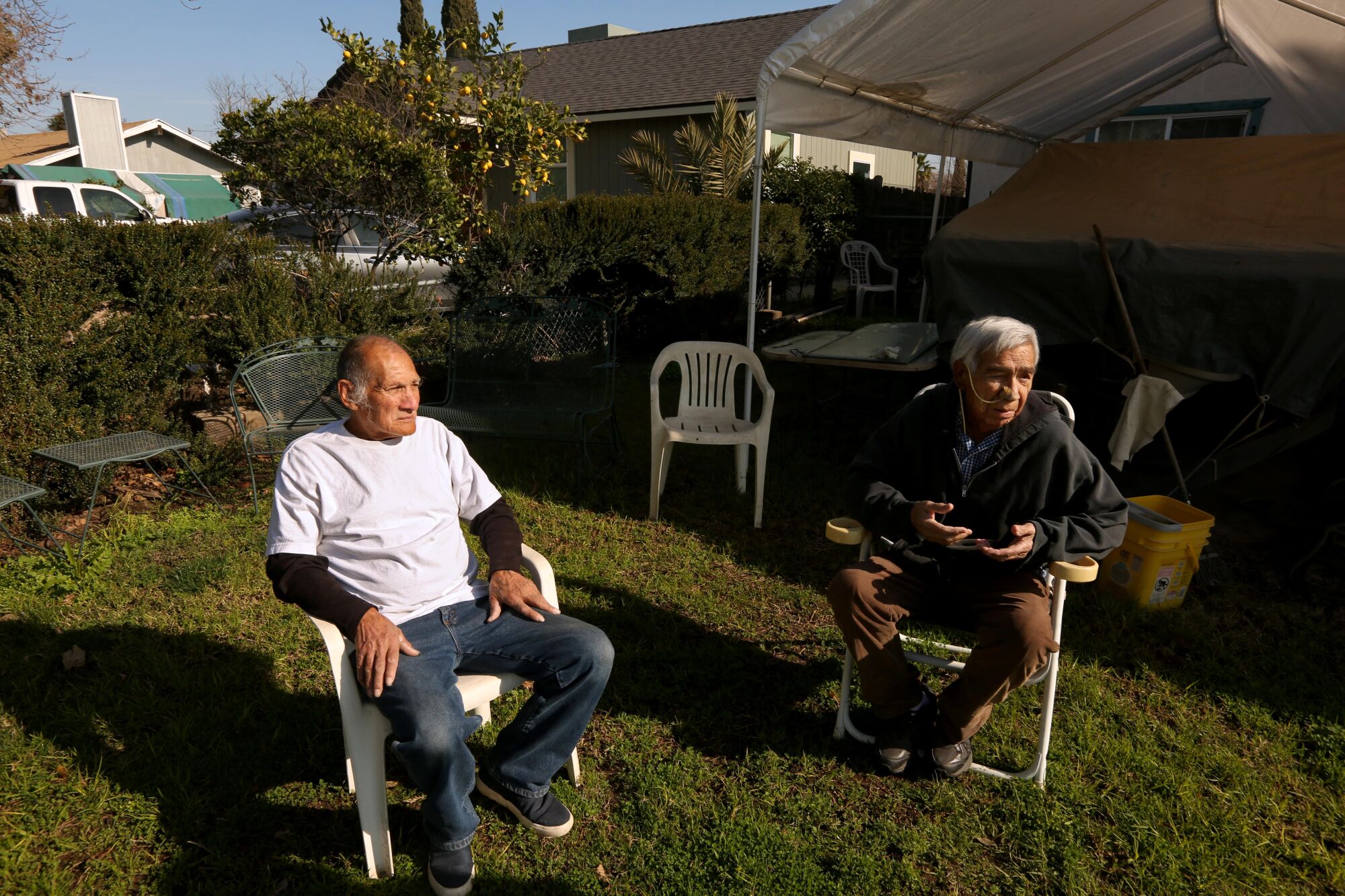 Two men sit in the front yard of a home in Goshen.
