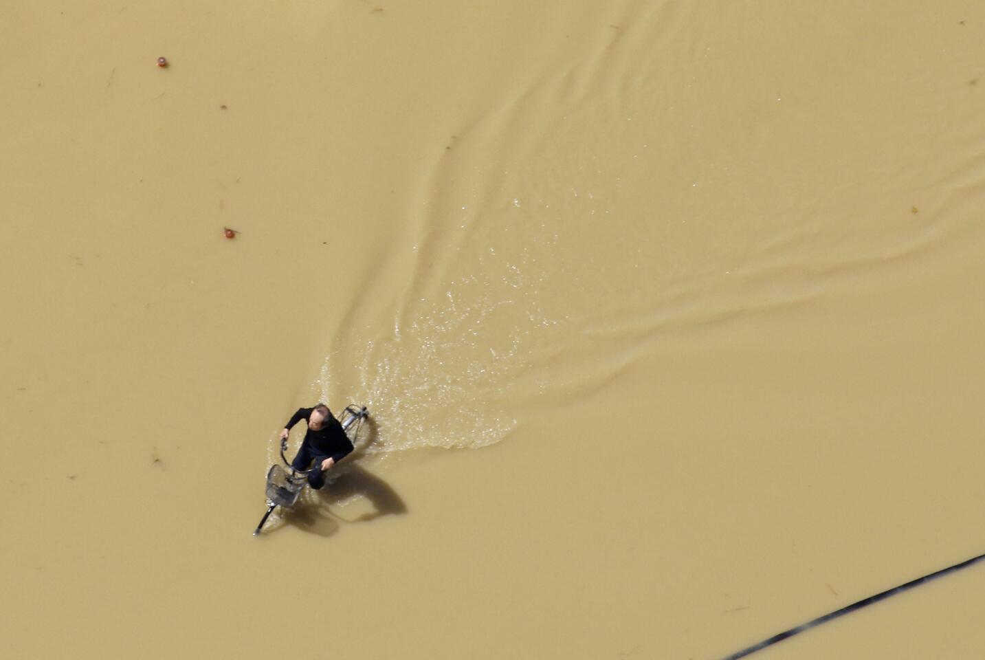 A man rides a bicycle in a road flooded with murky water in Joso, Japan, Sept. 11, 2015.