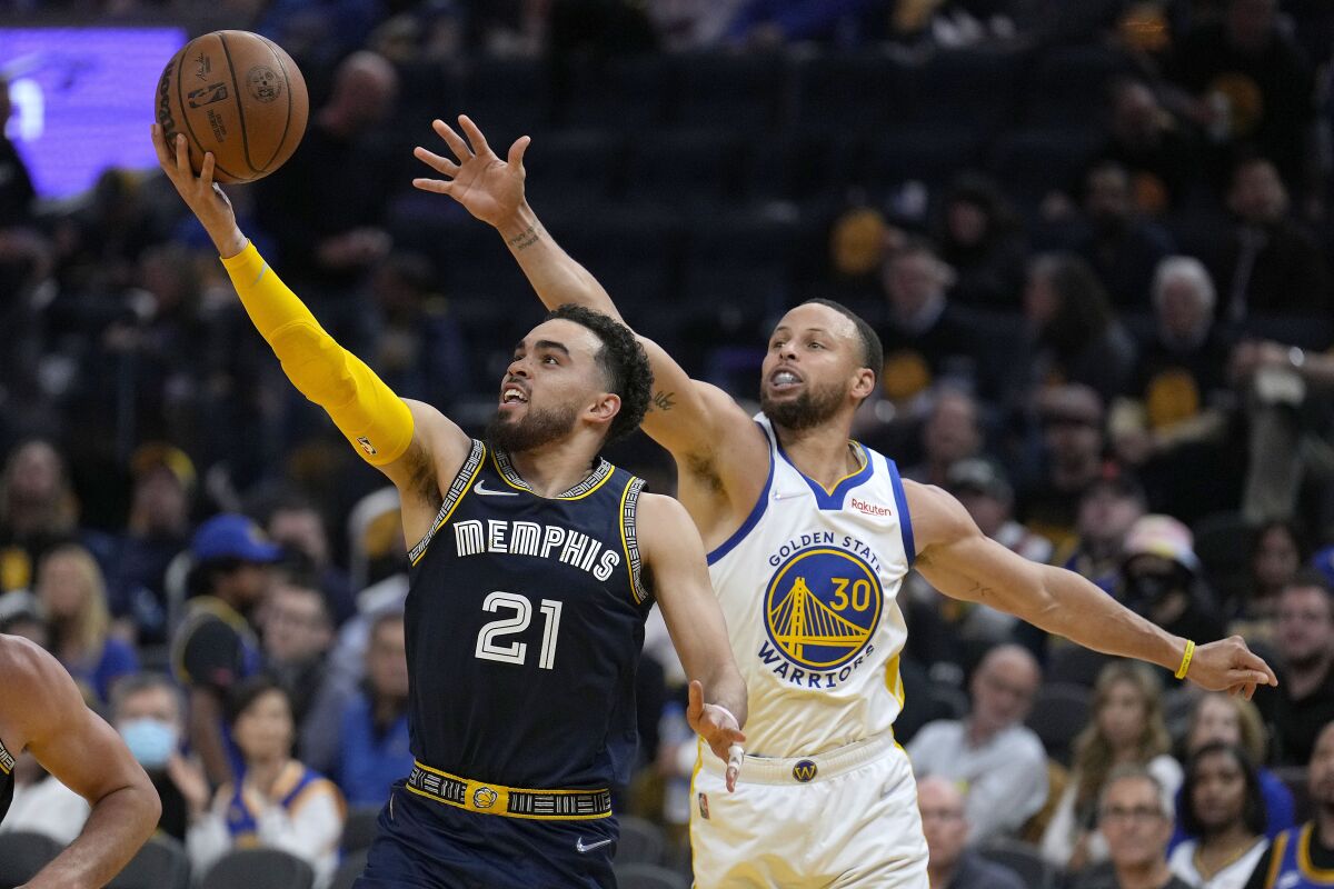 Tyus Jones (21), de los Grizzlies de Memphis, trata de conducir la pelota ante la presión de Stephen Curry (30), de los Warriors de Golden State, durante la segunda mitad del cuarto juego de la semifinal de la Conferencia Oeste, en San Francisco, el 9 de mayo de 2022. (AP Foto/Tony Avelar)